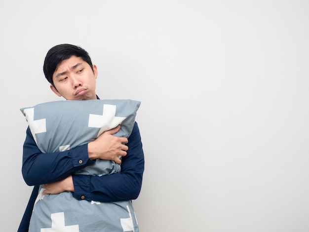 El hombre asiático abraza la almohada con sueño y aburrido mirando el espacio de la copia