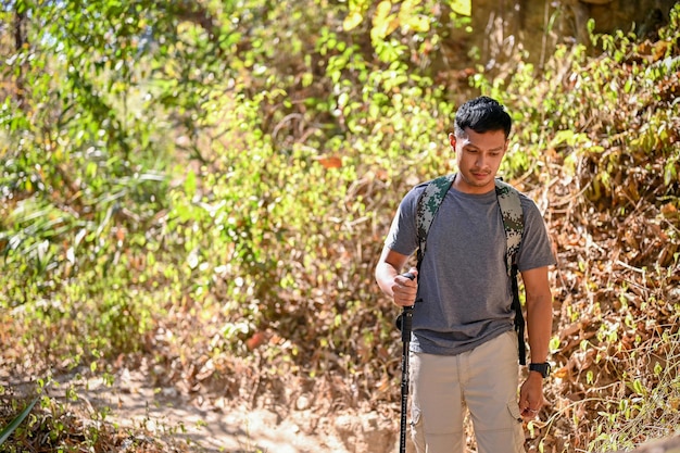 Hombre asiático activo con equipo de trekking senderismo senderismo solo en la montaña rocosa