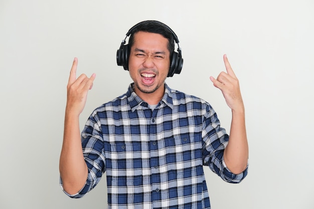 Hombre asiático adulto con auriculares disfrutando de la música con expresión emocionada