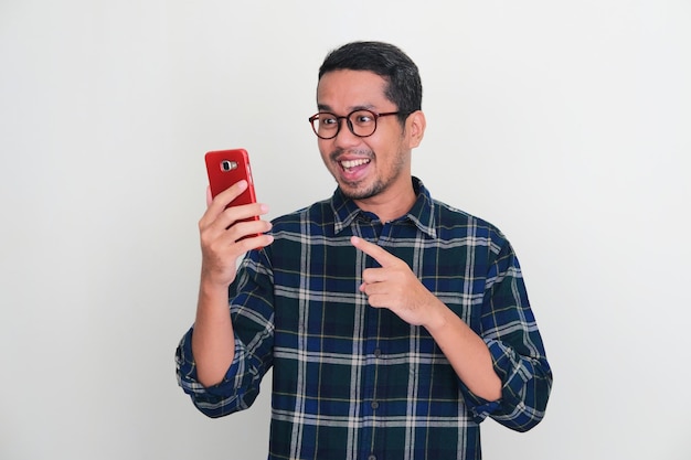 Hombre asiático adulto mirando a su teléfono con expresión feliz