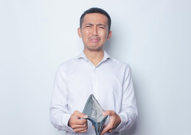 Foto hombre asiático adulto mostrando su billetera vacía con expresión