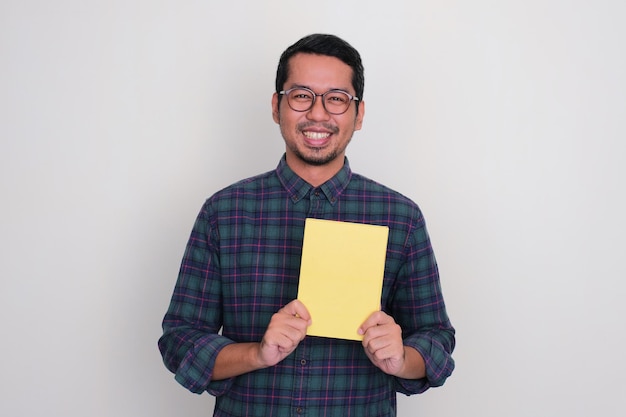 Hombre asiático adulto sonriendo feliz mientras sostiene un certificado de logro en blanco