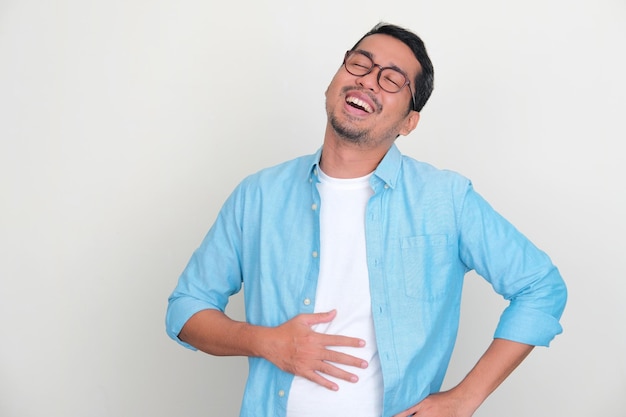 Hombre asiático adulto tocando su vientre con expresión de alivio