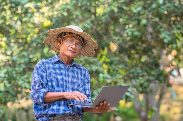 Hombre asiático agricultor con laptop afuera