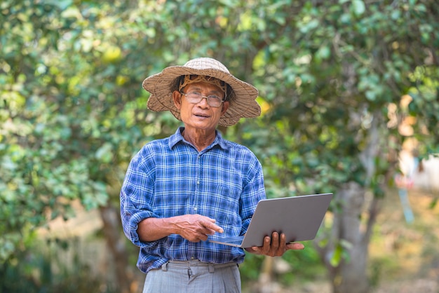 Hombre asiático agricultor con teléfono inteligente y concepto de negocio y tecnología portátil