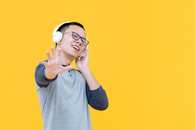 Hombre asiático con auriculares escuchando música y haciendo gesto de parada