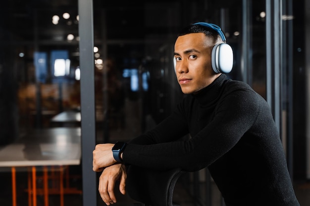 Hombre asiático con auriculares trabajando en línea y escuchando música en la oficina