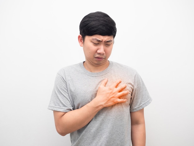 Hombre asiático camisa gris gesto dolor corazón fondo blanco.