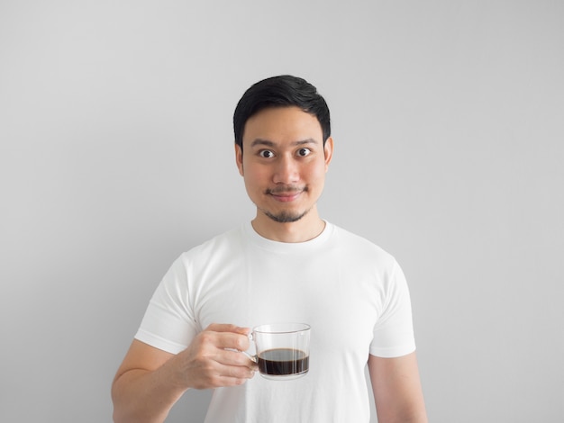 El hombre asiático en la camiseta blanca bebe una taza de café.