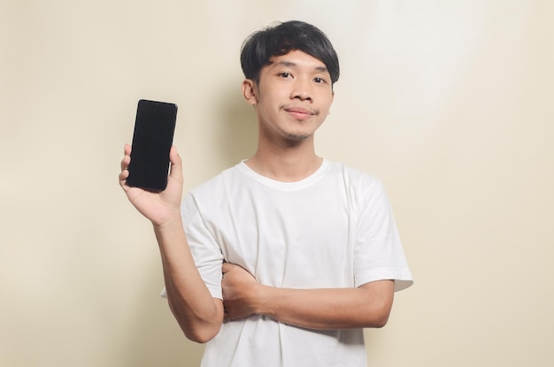 Hombre asiático con camiseta blanca con gesto mostrando su teléfono en un fondo aislado