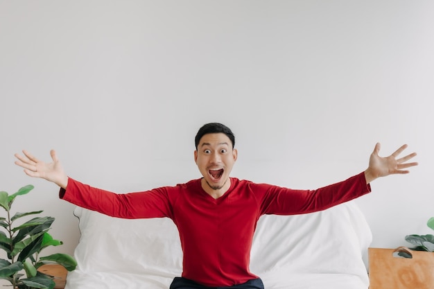 Hombre asiático de cara sorprendida en la casa con espacio de copia publicitaria en la pared