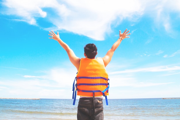 Hombre asiático en chaleco salvavidas manos arriba, viaje feliz, concepto de estilo de vida de libertad y viaje