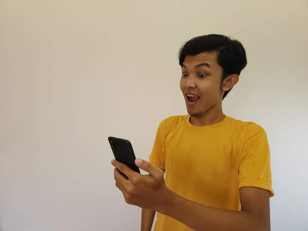 Hombre asiático chocado que mira el teléfono móvil