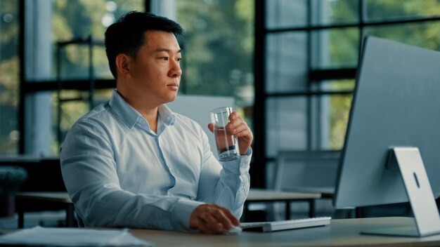 El hombre asiático coreano bebe un vaso de agua fresca y fría para mantener el equilibrio de la salud, el rejuvenecimiento, la energía, la atención médica.