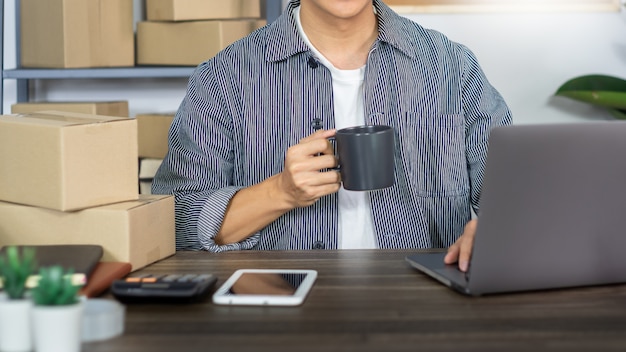 Hombre asiático empresario emprendedor emprendedor de pequeñas empresas sme hombre independiente que trabaja con la caja para el marketing en línea y la escena de entrega en la oficina en casa, concepto de vendedor de negocios en línea