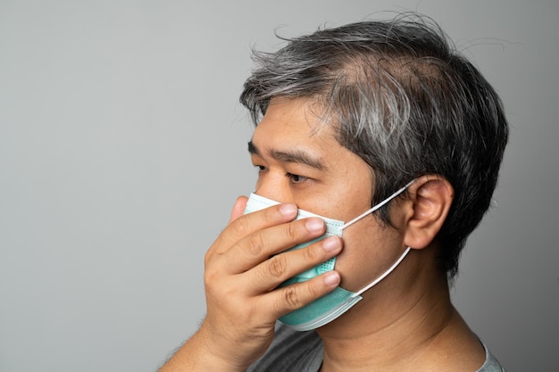 Hombre asiático enfermo con mascarilla médica y tosiendo y cubriéndose la boca