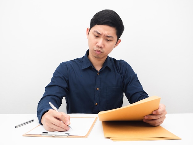 Hombre asiático escribiendo en el documento en la mesa emoción seria fondo blanco.