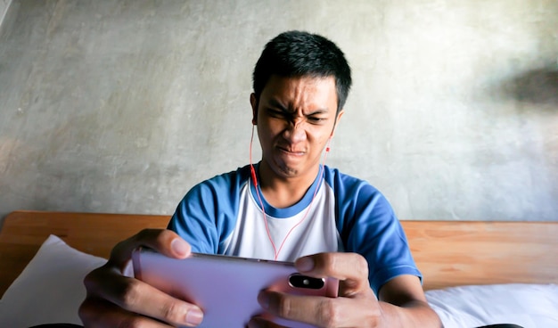 El hombre asiático está jugando en el dormitorio