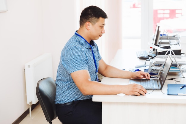 Un hombre asiático está trabajando en una computadora que el estudiante está estudiando estudiando el concepto de negocios en línea de dispositivos tecnológicos