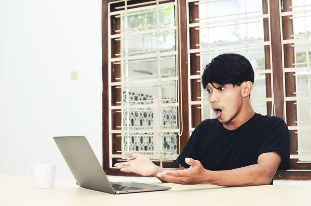 El hombre asiático estaba sentado apuntando a la computadora portátil