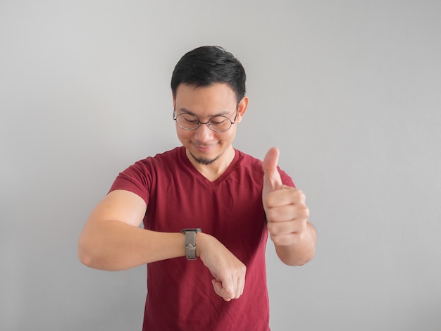 Hombre asiático feliz y sorprendido que está mirando su reloj.