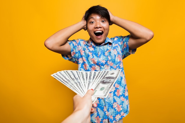 Hombre asiático feliz sorprendido recibiendo billetes de dinero