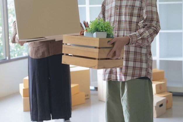 Un hombre asiático feliz y su amiga llevan sus pertenencias arriba mientras se mudan a un nuevo apartamento