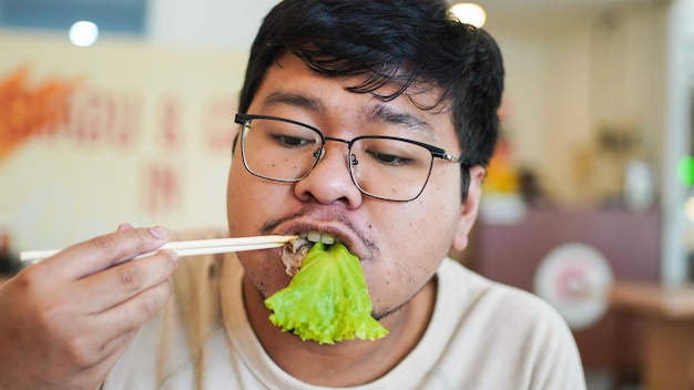 Hombre asiático con gafas come deliciosa lechuga en el restaurante