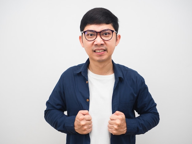 Hombre asiático con gafas sintiendo emoción enojada toque su camisa sobre fondo blanco.