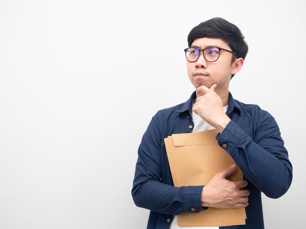 Hombre asiático con gafas sosteniendo el gesto del sobre del documento pensando mirando el espacio de la copia