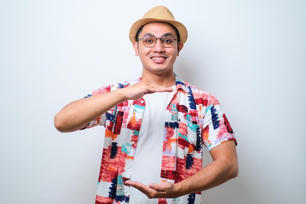 Hombre asiático gesticulando con las manos mostrando un símbolo de medida de signo grande y grande sonriendo mirando el concepto de medición de la cámara