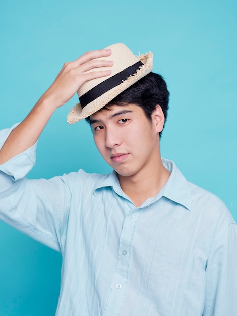 Hombre asiático guapo con una camisa azul con un sombrero