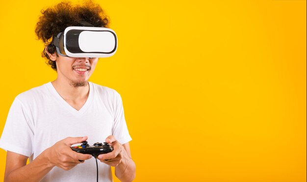 Un hombre asiático guapo con el pelo rizado juega un juego que usa auriculares de realidad virtual o vidrio VR