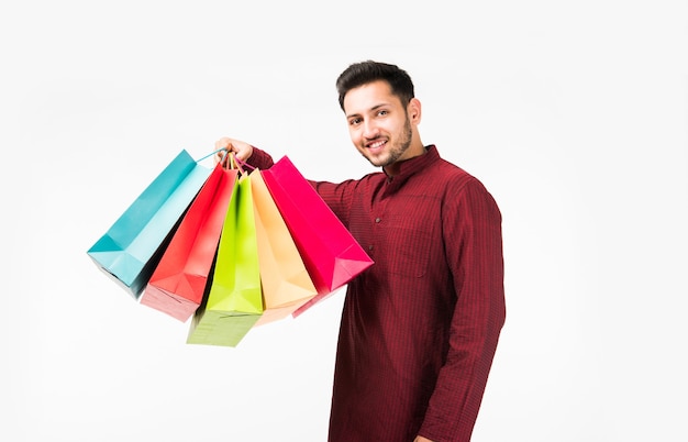 Hombre asiático indio en ropa étnica con bolsas de la compra, que se encuentran aisladas sobre fondo blanco.