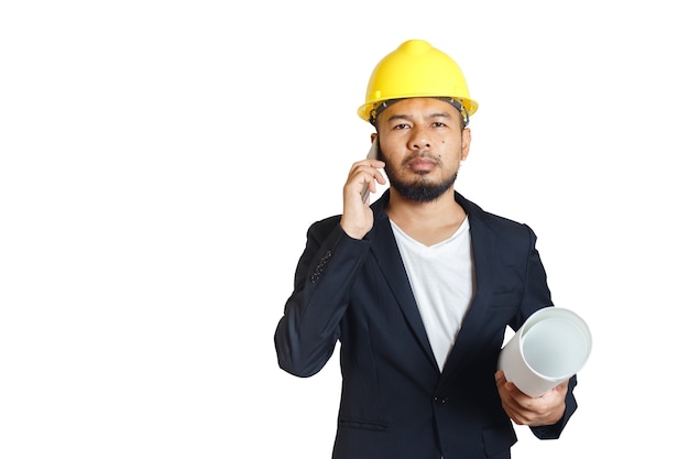 El hombre asiático de la ingeniería lleva el teléfono que habla del casco y que sostiene el modelo en el fondo blanco. capataz de control de la construcción. trazado de recorte.