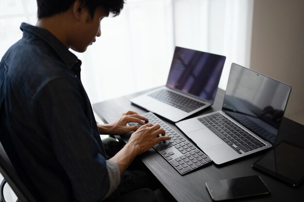 Hombre asiático ingeniero de software Trabajando en la computadora en el escritorio de la oficina para escribir código de programa Ingeniero de software de TI encontrando errores soporte técnico devops creando digital