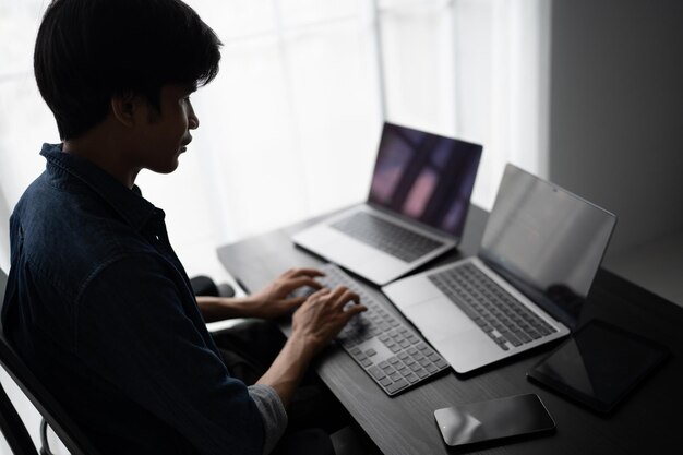 Hombre asiático ingeniero de software Trabajando en la computadora en el escritorio de la oficina para escribir código de programa Ingeniero de software de TI encontrando errores soporte técnico devops creando digital