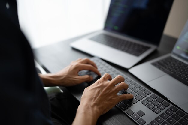 Hombre asiático ingeniero de software Trabajando en la computadora en el escritorio de la oficina para escribir código de programa Ingeniero de software de TI encontrando errores soporte técnico devops creando digital
