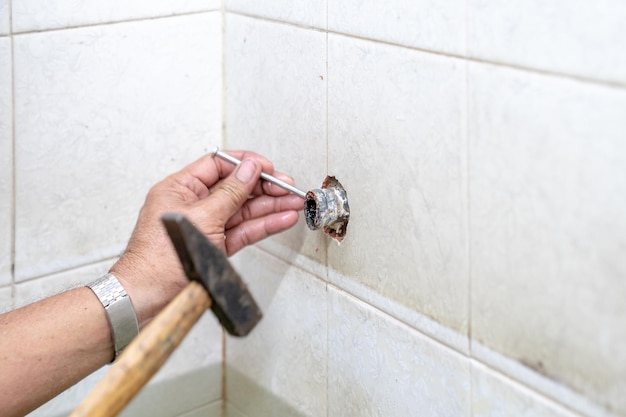 El hombre asiático intenta arreglar y reparar la ducha de tubería en el antiguo baño