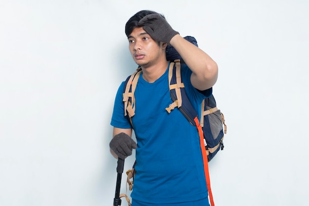 Hombre asiático joven excursionista con una mochila sensación de cansancio aislado sobre fondo blanco.