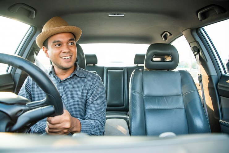 Hombre asiático joven sonriente que conduce el coche.