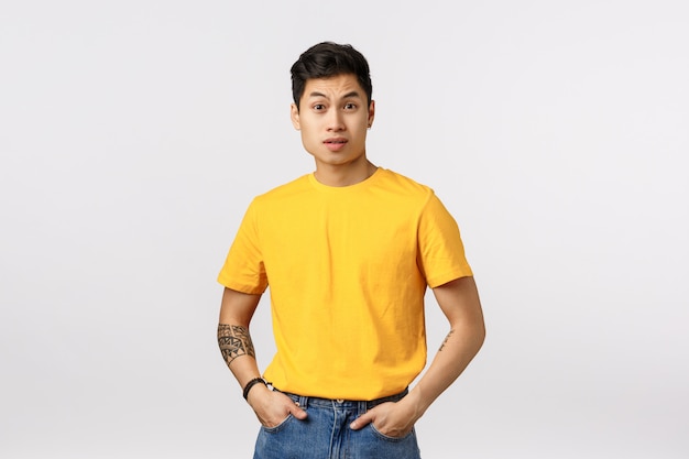 Hombre asiático lindo en camiseta amarilla posando