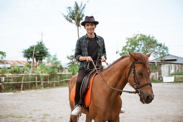 hombre asiático, llevando, sombrero vaquero, equitación, caballo, y, tenencia, riendas