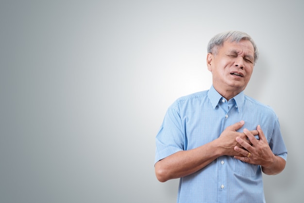 Un hombre asiático más viejo que agarra y tiene dolor en el pecho causa de un ataque al corazón.