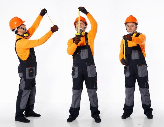 El hombre asiático mayor usa el casco anaranjado de la camisa del uniforme y el guante de cuero como mano de obra del sitio de construcción del ingeniero. Longitud total de cinta métrica de retención masculina pequeña corta muchos actos, fondo blanco aislado