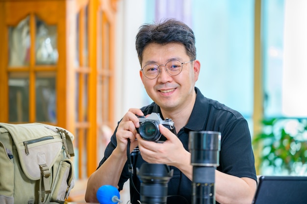 Un hombre asiático de mediana edad cuyo pasatiempo es la cámara SLR de película de 35 mm / 135 mm