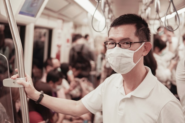 Hombre asiático de mediana edad con gafas y mascarilla médica, brote de coronavirus de Wuhan, contaminación del aire y concepto de salud