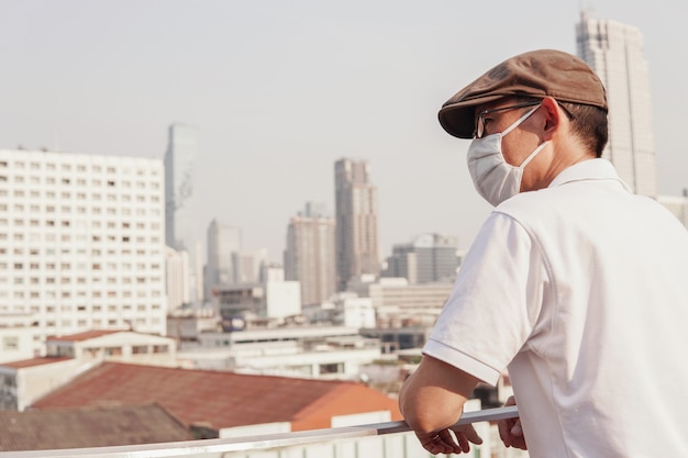 Hombre asiático de mediana edad con gafas y mascarilla médica, brote de coronavirus de Wuhan, contaminación del aire y concepto de salud
