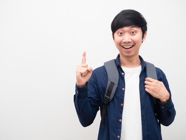 Hombre asiático con mochila escolar, cara de sonrisa, señalar con el dedo hacia arriba obtener espacio de copia de retrato de idea