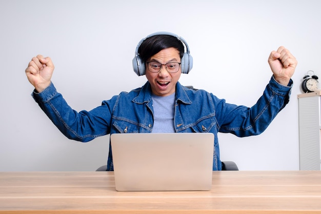 Hombre asiático mostrando alegría en la pantalla del portátil